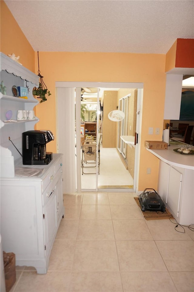 kitchen featuring white cabinetry, a textured ceiling, and light tile patterned floors