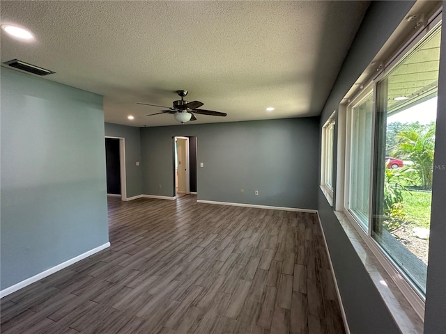 empty room with ceiling fan, a textured ceiling, and dark hardwood / wood-style flooring