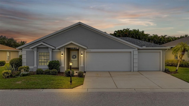 ranch-style house with a garage and a lawn