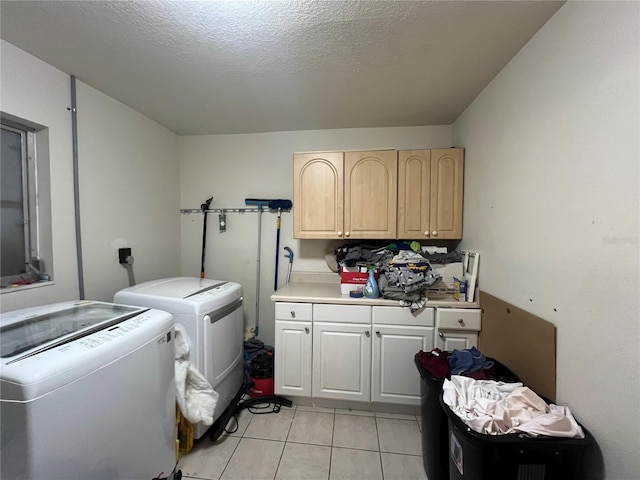 washroom featuring cabinets, washing machine and dryer, light tile patterned floors, and a textured ceiling