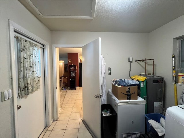 clothes washing area featuring washer / clothes dryer, electric water heater, a textured ceiling, and light tile patterned floors