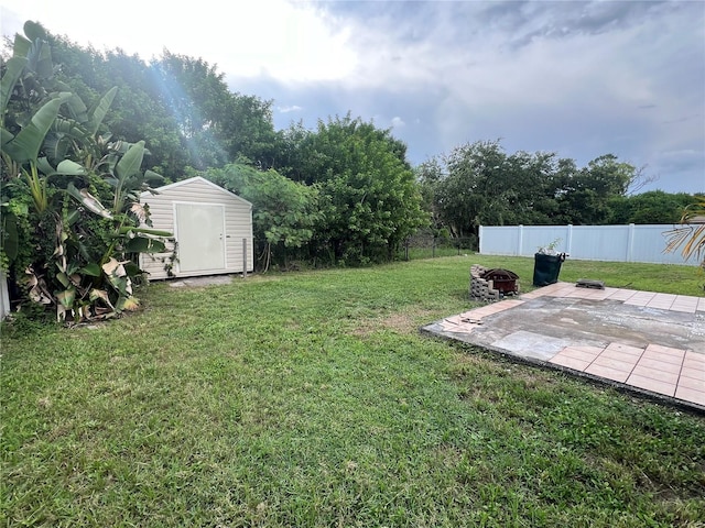 view of yard with a shed, a fire pit, and a patio area