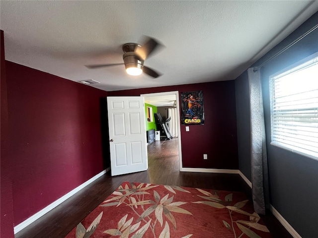 bedroom with ceiling fan, dark hardwood / wood-style floors, and a textured ceiling