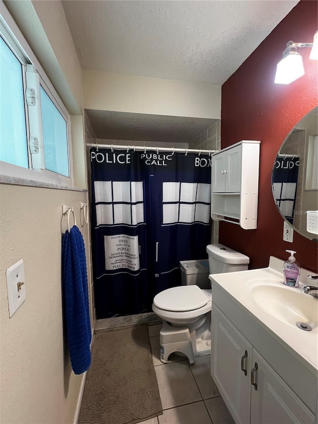 bathroom featuring curtained shower, tile patterned flooring, vanity, toilet, and a textured ceiling