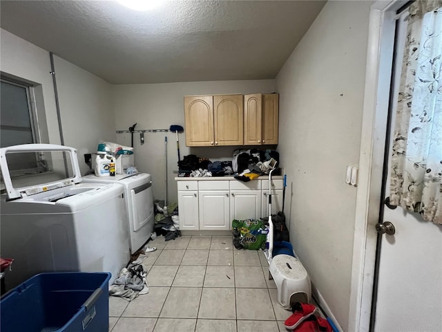 laundry area featuring light tile patterned floors, washing machine and dryer, cabinets, and a textured ceiling