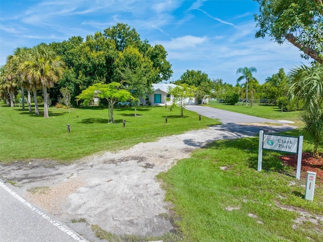 view of community with driveway, a yard, and an attached garage