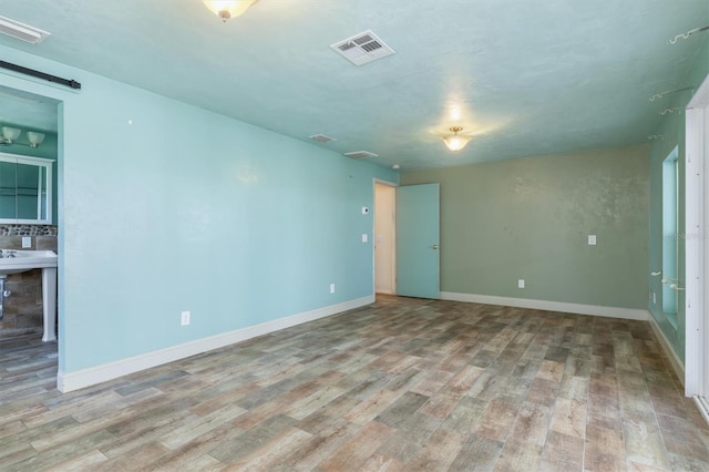 empty room featuring baseboards, visible vents, and light wood finished floors