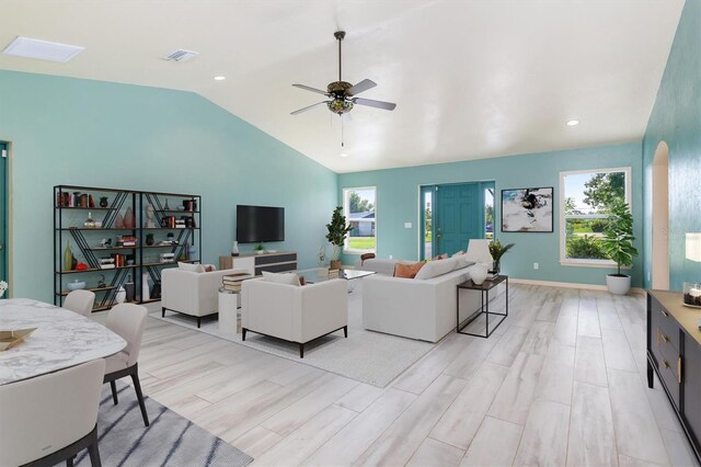 living room featuring light wood finished floors, baseboards, visible vents, a ceiling fan, and vaulted ceiling