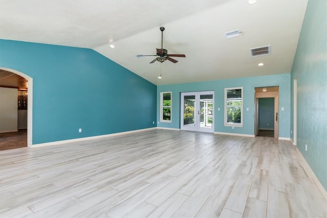 unfurnished living room featuring light wood finished floors, visible vents, arched walkways, a ceiling fan, and french doors