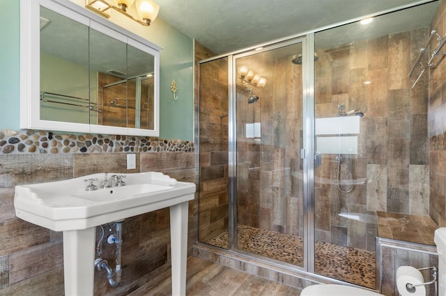 bathroom with tile walls, a shower with door, hardwood / wood-style flooring, and tasteful backsplash