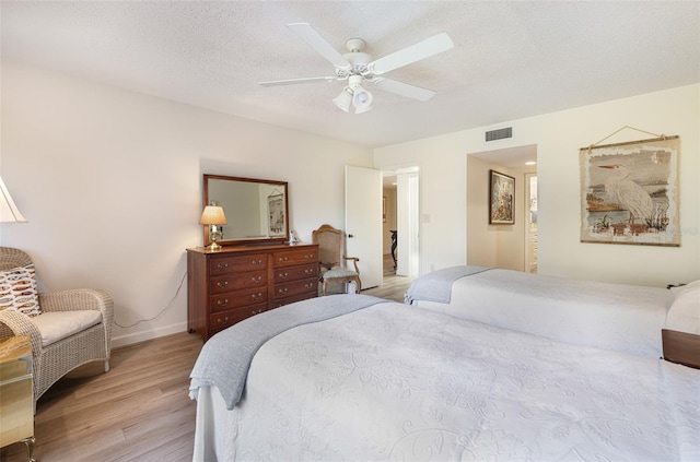 bedroom with light wood-type flooring, a textured ceiling, and ceiling fan