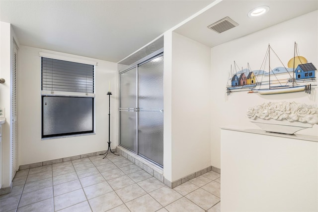 bathroom with an enclosed shower and tile patterned floors