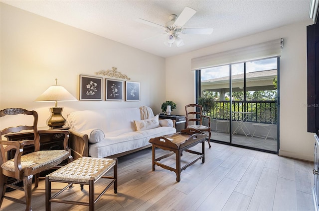 living room with ceiling fan, a textured ceiling, and light hardwood / wood-style flooring