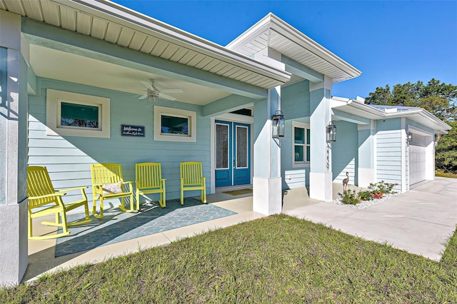 view of exterior entry with a garage, a yard, covered porch, and ceiling fan