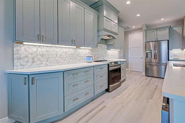 kitchen with stainless steel appliances, light stone counters, light hardwood / wood-style floors, and decorative backsplash