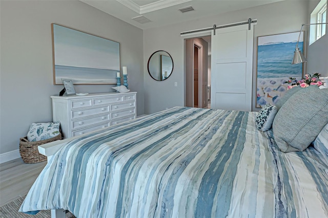 bedroom featuring ornamental molding, a barn door, and light hardwood / wood-style floors