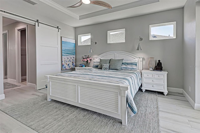 bedroom with a raised ceiling, crown molding, a barn door, and ceiling fan