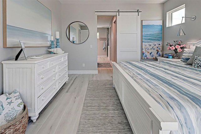 bedroom with light hardwood / wood-style flooring and a barn door