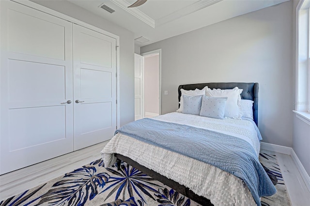 bedroom featuring crown molding, light hardwood / wood-style floors, and a closet