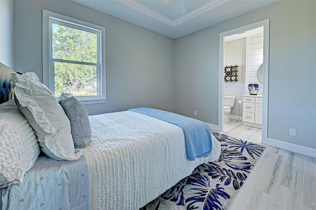 bedroom with connected bathroom and light hardwood / wood-style floors