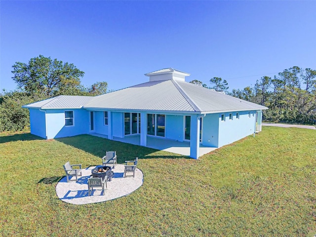 back of house featuring a yard, a patio area, and a fire pit