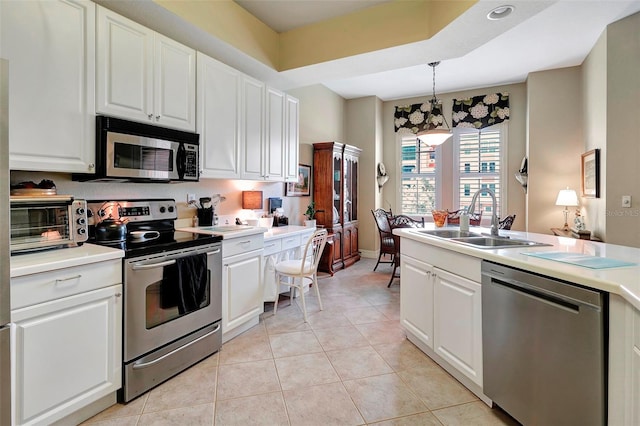 kitchen featuring appliances with stainless steel finishes, decorative light fixtures, white cabinets, and sink