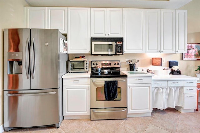 kitchen featuring stainless steel appliances, light tile patterned flooring, and white cabinetry