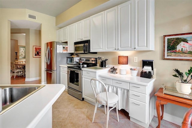 kitchen with sink, stainless steel appliances, white cabinets, and light tile patterned floors