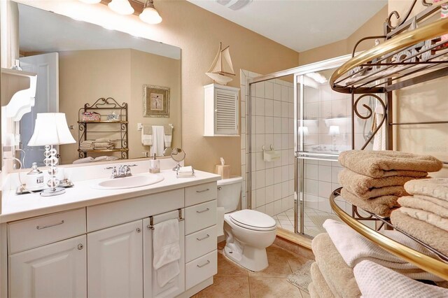 bathroom featuring tile patterned flooring, a shower with shower door, vanity, and toilet