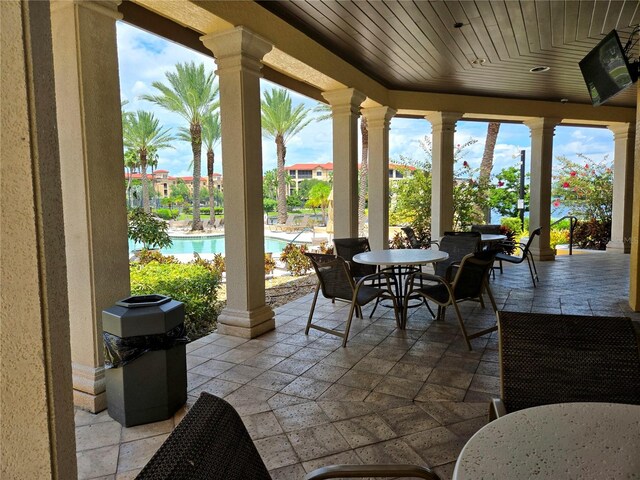 sunroom featuring wood ceiling, plenty of natural light, and decorative columns