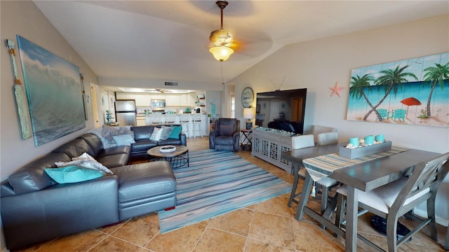 living room with ceiling fan, vaulted ceiling, and light tile patterned floors