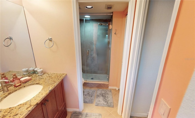 bathroom with a shower with shower door, vanity, and tile patterned floors