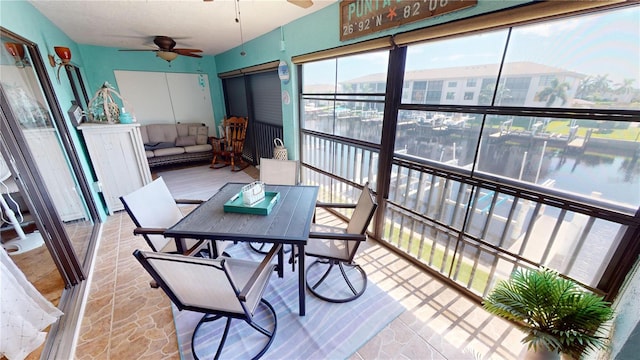 sunroom / solarium with a water view and ceiling fan