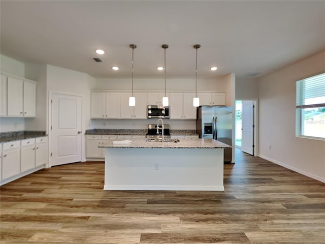 kitchen with light hardwood / wood-style floors, white cabinetry, stainless steel appliances, and a center island with sink