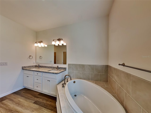 bathroom with vanity, tiled bath, and hardwood / wood-style flooring