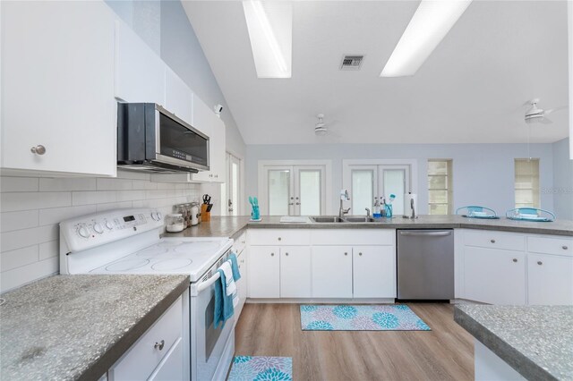 kitchen with stainless steel appliances, light wood-type flooring, vaulted ceiling, and sink