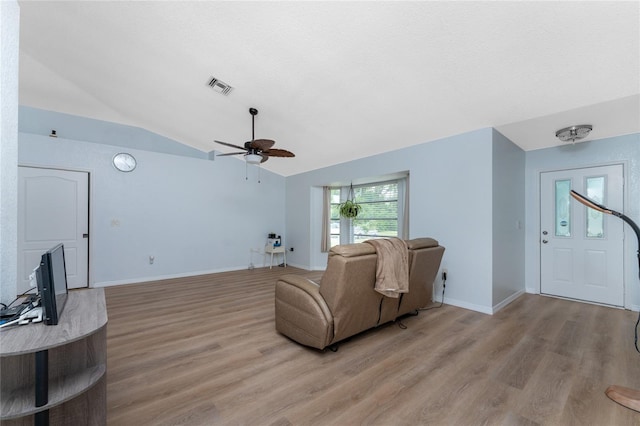 living area with lofted ceiling, baseboards, visible vents, and light wood finished floors