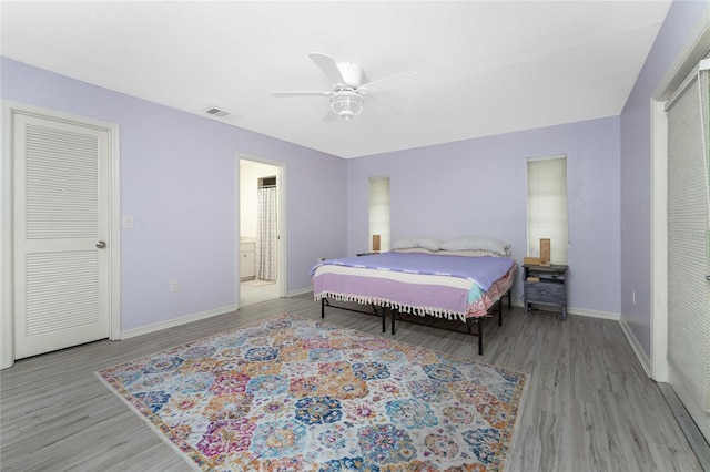 bedroom featuring visible vents, baseboards, ceiling fan, wood finished floors, and ensuite bathroom