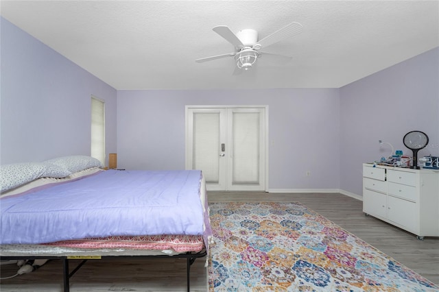 bedroom with french doors, ceiling fan, a textured ceiling, wood finished floors, and baseboards