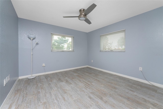 empty room featuring ceiling fan, baseboards, and wood finished floors