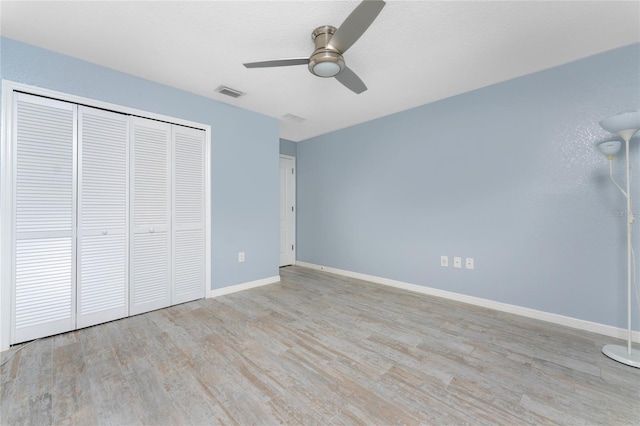 unfurnished bedroom with baseboards, visible vents, ceiling fan, wood finished floors, and a closet