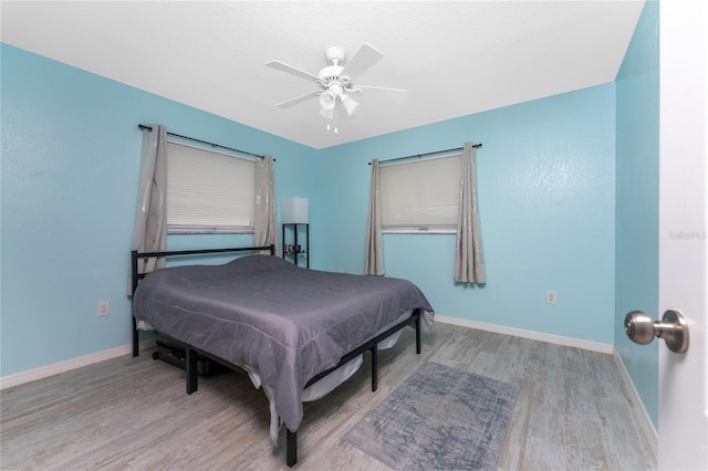 bedroom featuring ceiling fan, baseboards, and wood finished floors