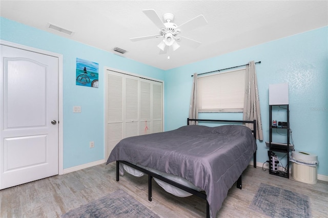 bedroom featuring a closet, wood finished floors, visible vents, and baseboards