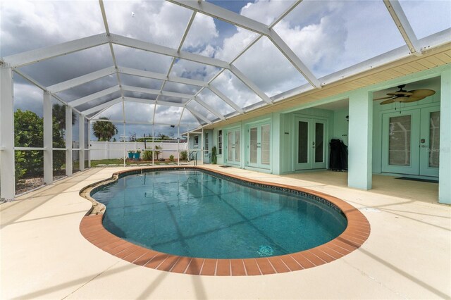 view of swimming pool featuring ceiling fan, glass enclosure, a patio area, and french doors