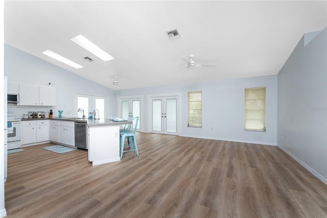kitchen with white cabinets, appliances with stainless steel finishes, french doors, visible vents, and lofted ceiling with skylight