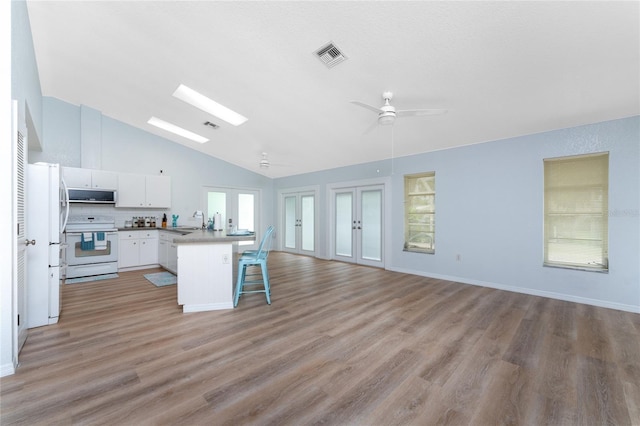 kitchen with white electric range oven, a sink, a breakfast bar area, french doors, and open floor plan