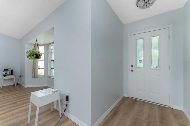 foyer with baseboards, vaulted ceiling, and wood finished floors