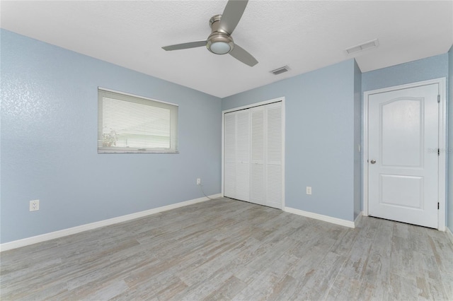 unfurnished bedroom with visible vents, light wood-style floors, baseboards, and a closet