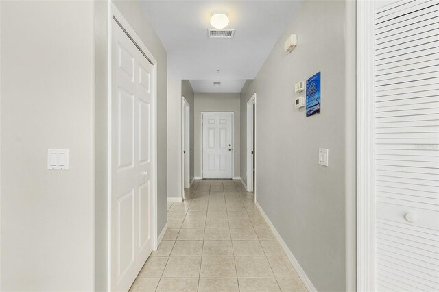 hallway with baseboards, visible vents, and light tile patterned flooring