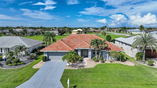 view of front of house featuring a tiled roof, concrete driveway, a residential view, and a front yard